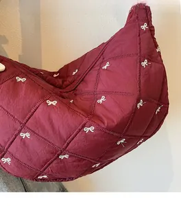 Detailed close-up of burgundy quilted tote bag with white bow embroidery and diamond stitching