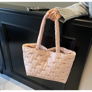 Close-up of pink quilted tote bag with diamond stitching and mini bow details