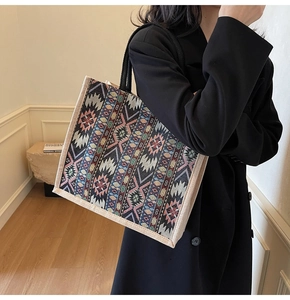 Detail of woven tote bag featuring ethnic geometric patterns and sturdy black handles
