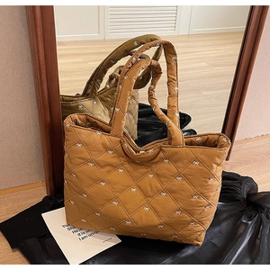Detail of quilted caramel brown tote bag with white bow patterns and padded handle