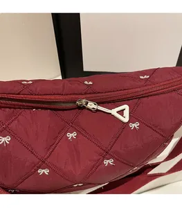 Detail of smooth zipper closure on wine red quilted shoulder bag with bow embroidery
