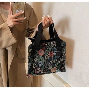 Detail of floral tapestry tote with black canvas straps and metal snap button closure