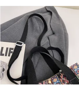 Detail of adjustable black canvas shoulder strap with white buckle on jacquard woven tote