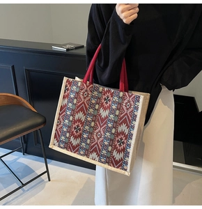 Close-up of ethnic geometric pattern weaving and red rope handles on large linen tote bag