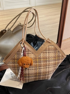Retro plaid tote bag with brown leather handles and a cute dog charm on a silk surface