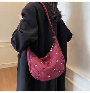 Close-up of wine red quilted hobo bag featuring white bow patterns and soft nylon texture
