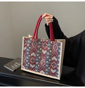 Close-up of ethnic geometric linen tote bag featuring red braided rope handles and texture