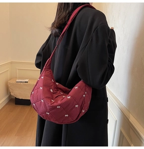 Detail of burgundy quilted crescent bag featuring delicate white bow embroidery