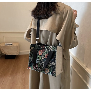 Detail of floral tapestry tote with detachable black straps shown on a model