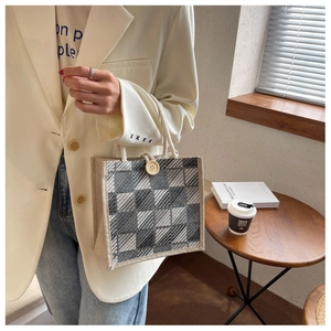 Close-up of retro plaid canvas handbag featuring a wooden button and woven handle