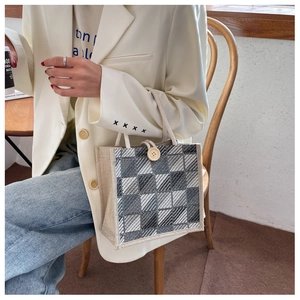 Detail of linen tote bag with black and white grid pattern and round wooden button