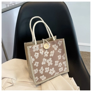 Detail of linen tote bag featuring 3D floral embroidery and round wooden button closure
