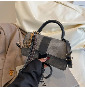 Détail du sac en denim gris avec poignées en cuir noir et breloque de raquette dorée