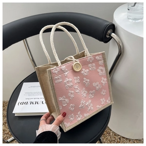 Detail of pink linen tote bag featuring 3D floral motifs and white cotton rope handles