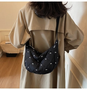 Close-up of black quilted dumpling bag with white bow pattern and smooth silver zipper
