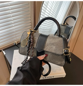 Détail du sac à main en denim gris avec garniture en cuir noir et breloque dorée