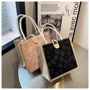 Detail of mini linen tote bags with 3D floral accents and woven handles in soft lighting