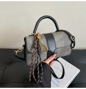 Détail du sac en toile grise et cuir noir avec pendentif de tennis et cordon tressé