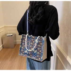 Detail of bohemian woven canvas tote with ethnic patterns and adjustable blue strap