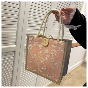 Detail of pink linen tote bag featuring 3D white flower applique and woven rope handles