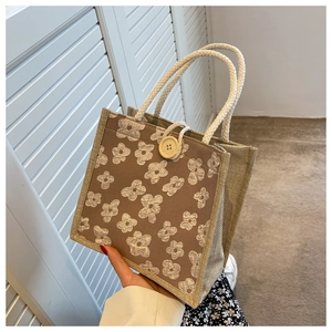 Detail of coffee linen handbag with yellow floral embroidery and woven cotton handles