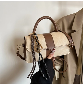 Détail du sac beige avec finitions en cuir marron et pendentif de raquette de tennis