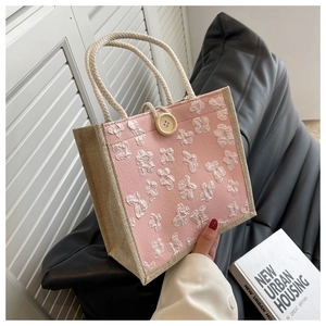 Pink linen tote bag featuring a white 3D flower, wooden button, and rope handle detail