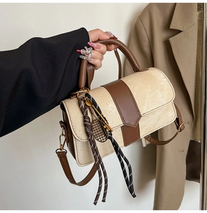 Détail d'un sac en daim crème avec bandoulière en cuir brun et breloque de tennis or