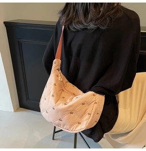 Detailed view of pink quilted hobo bag with small bow embroidery and soft fabric texture