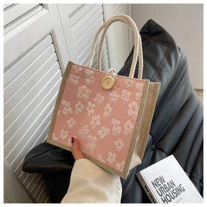 Detail of pink linen tote bag featuring 3D floral petals and wooden button closure