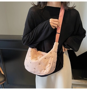 Detailed view of pink quilted nylon crossbody bag with small bow embroidery and strap
