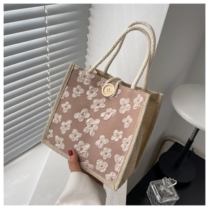 Detail of pink linen tote with floral embroidery and natural jute sides and rope handle