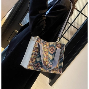 Close-up of ethnic jacquard woven tote bag with adjustable strap on black wool coat