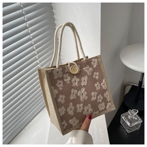 Detailed texture of 3D floral appliques and braided rope handles on linen tote bag