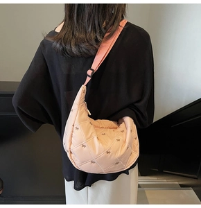 Quilted pink crescent bag with bow embroidery shown on shoulder against a staircase background