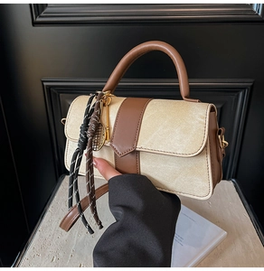 Détail du sac en tissu beige et cuir marron avec pendentif de mini raquette de tennis