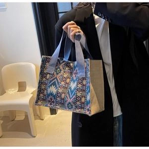 Close-up of geometric woven tote bag with blue trim and ethnic patterned details