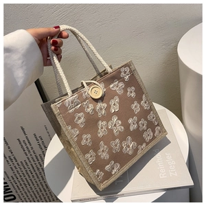 Close-up of linen tote bag featuring 3D floral accents and twisted rope handles