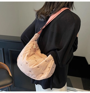 Detail view of pink quilted half-moon crossbody bag with dark bow embroidery pattern