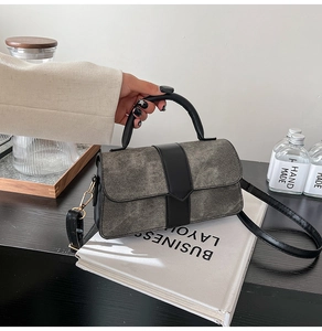 Détail du sac à main en cuir gris givré avec finitions noires et boucles dorées