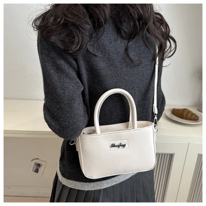 Detail view of cream white crossbody bag with adjustable strap and metal hardware
