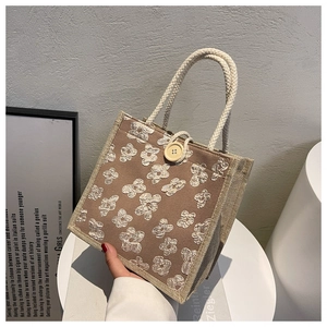 Detail of linen tote bag featuring 3D floral embroidery and wooden button closure