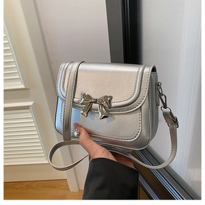 Détail du sac bandoulière argenté avec boucle nœud en métal et texture en cuir PU