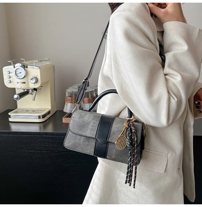 Détail du sac bandoulière gris et noir avec foulard décoratif et breloque raquette dorée