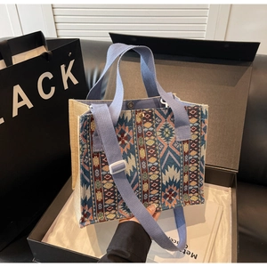 Close-up of geometric jacquard woven tote bag with a magnetic metal clasp and long strap