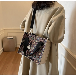 Ethnic pattern crossbody bag with woven details and detachable strap on beige coat