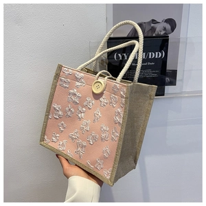 Close-up of pink linen tote bag with white floral texture and natural jute side details