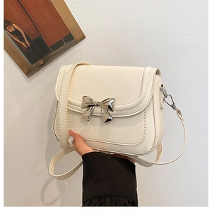Détail de la boucle de nœud en métal argenté sur le sac bandoulière en similicuir crème