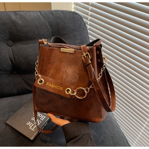 Macro shot of brown PU leather bucket bag featuring gold hardware and fashion embossing