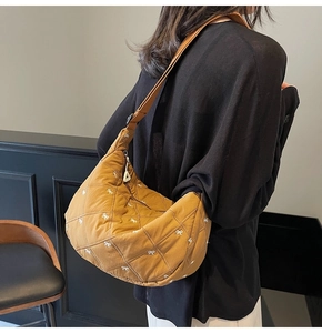 Detail of tan quilted hobo bag with small white bow embroidery and adjustable strap